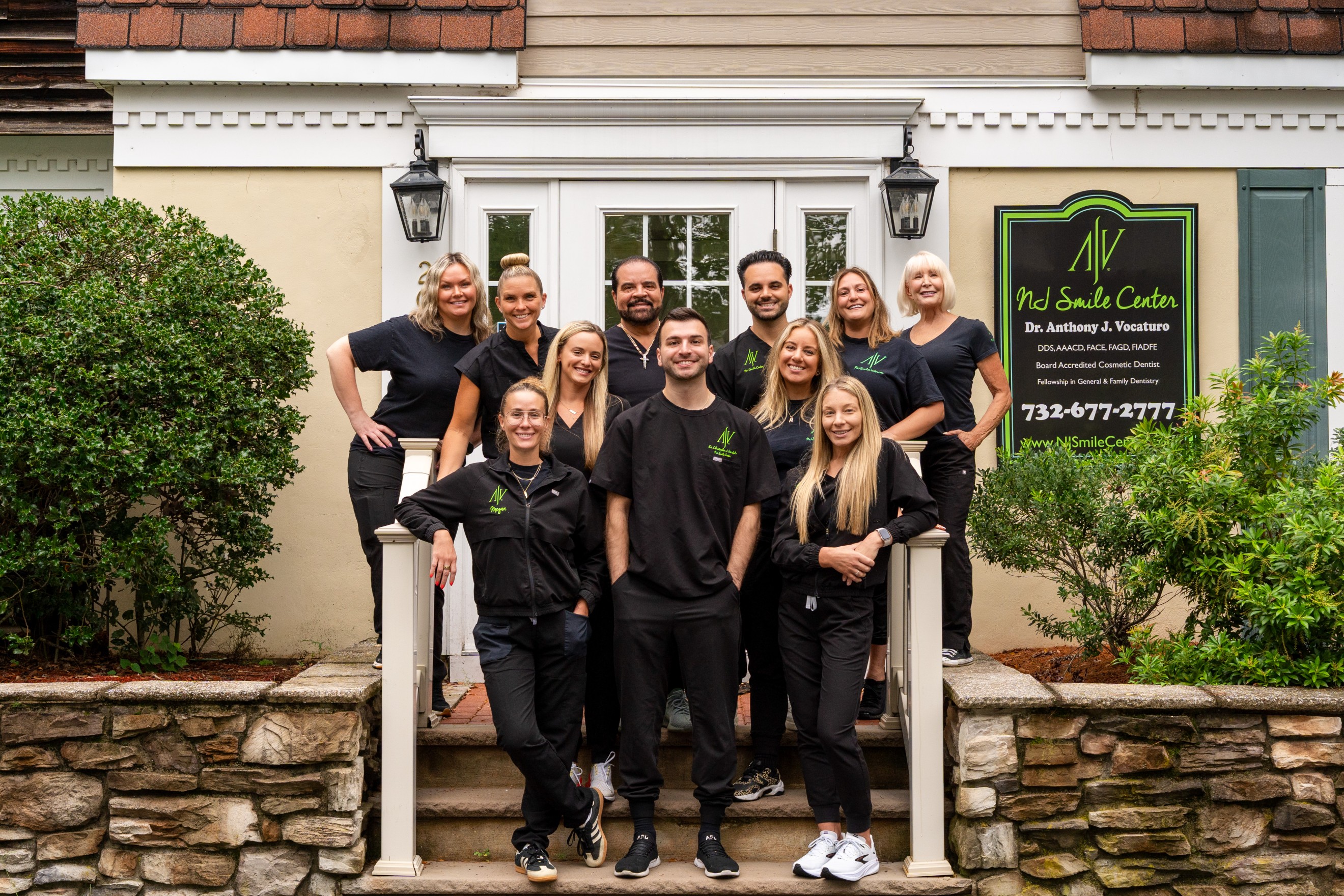 The NJ Smile Center doctors and team in black scrubs on the front steps of the Colts Neck office